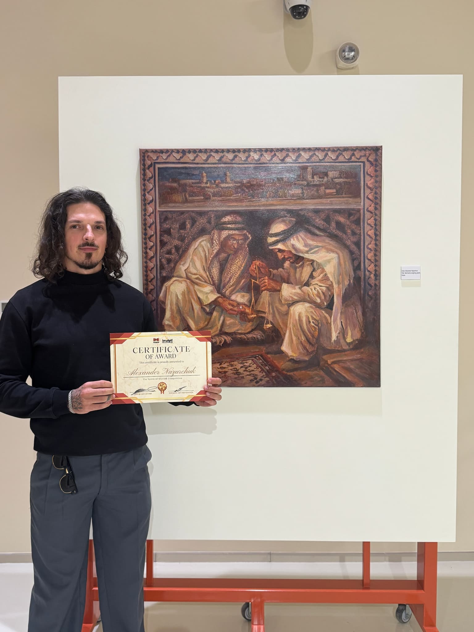 Artist with certificate beside the Spirit of Sharjah painting